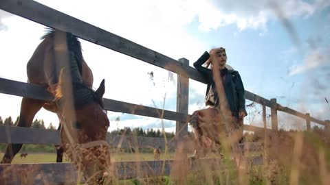 Dreamy female leaning on horse enclosure