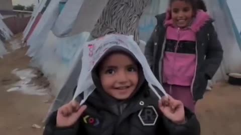 5 years old child taking cover from rain using a plastic bag in Gaza