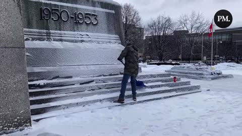 Supporters of the Freedom Convoy shovel snow at the National War Memorial in Ottawa