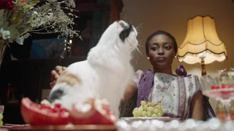 A Woman Petting Her Cat On The Dining Table