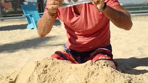 man finds money in the sand on the beach