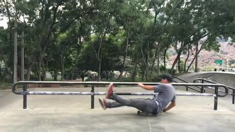 Blue shirt black hat tries to grind rail and falls on skateboard