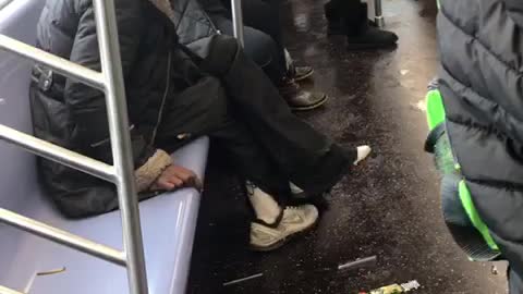 Man in pink white beanie smokes on a subway train