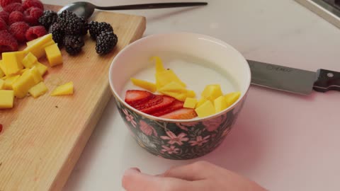 Preparing a bowl with yogurt and fruit