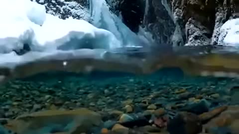 Snow falling on crystal clear Alaskan glacial meltwater captured by photographer John Derting