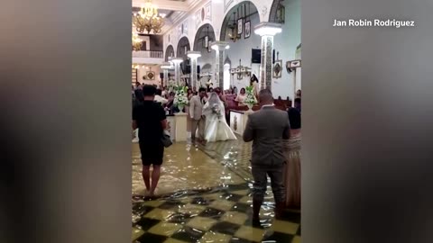 Filipino bride wades down flooded aisle after typhoon