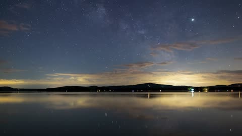 Night sky with stars at a calm lake, time lapse