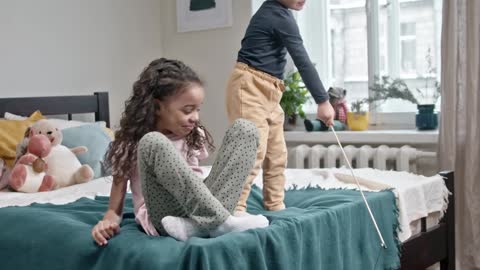 Kids Playing Catch The Bait With Their Cat In The Bedroom