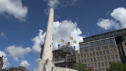 Netherlands Amsterdam dam square obelisk and flags against clouds 2