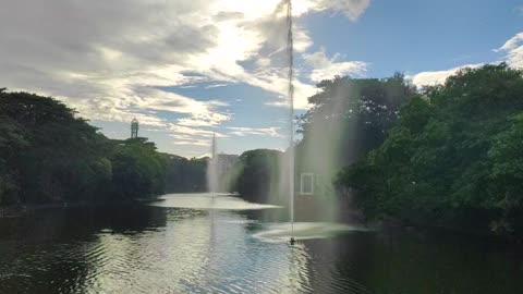 Beautiful Fountain in a Lake at Green Nature with Blue Sky and White Cloud