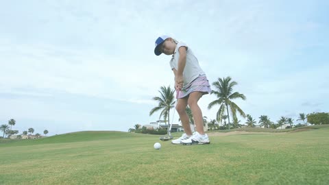 girl hitting a golf ball