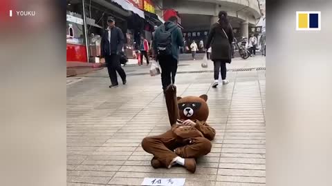 Man in bear costume lays on