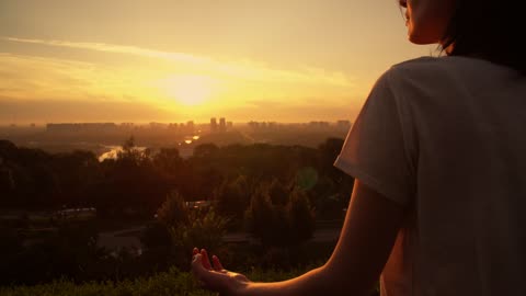 Woman meditating during sunset on the hill outside New York city