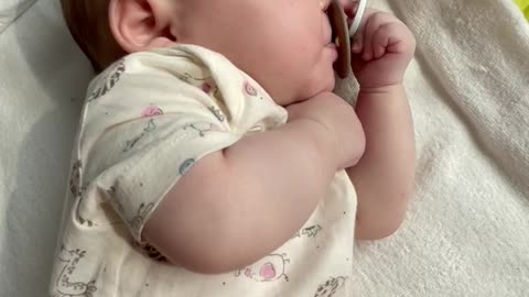 Baby is using the pacifier by herself