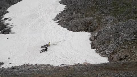 Person guy drives motorcycle up white sand rocky hill falls off into sand