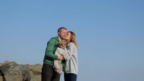 young couple walking on the beach with the dog. spring beach with snow