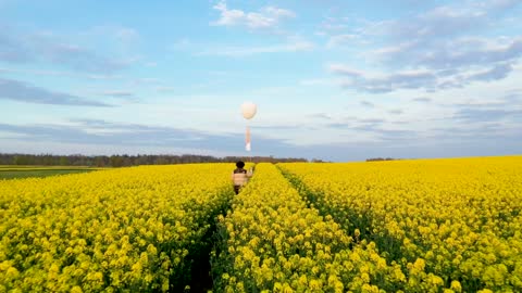 Walking on a flower field with a white balloon in hand