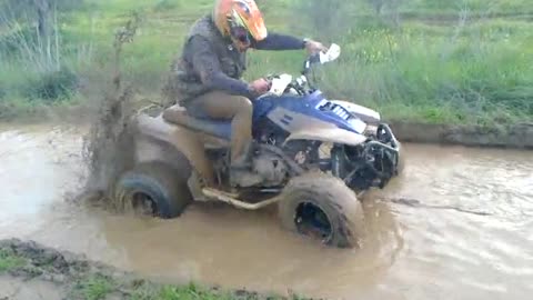 A bumbling biker with mud and water on the road