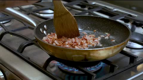 Frying diced bacon in a skillet