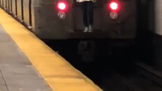 Guy white long riding behind moving subway train