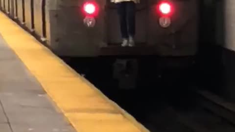 Guy white long riding behind moving subway train