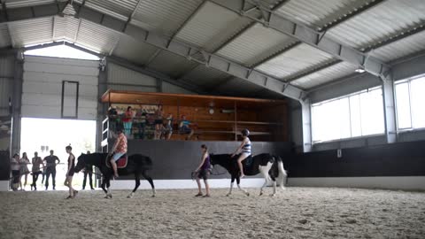 Children are trained to ride horses in the aviary on the sand