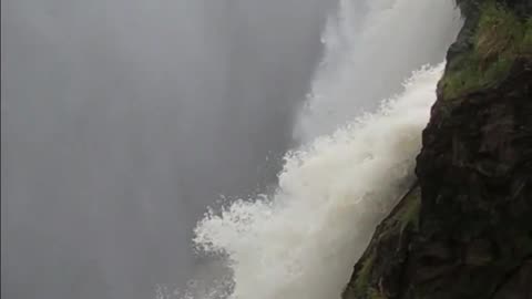 Two Men Standing at the Falls’ Steep Precipice with a View of the Drop-Off