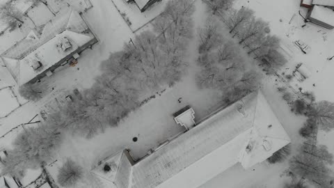 The quadrocopter descends from a great height in the winter in the village