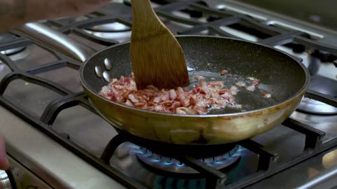 Frying diced bacon in a skillet