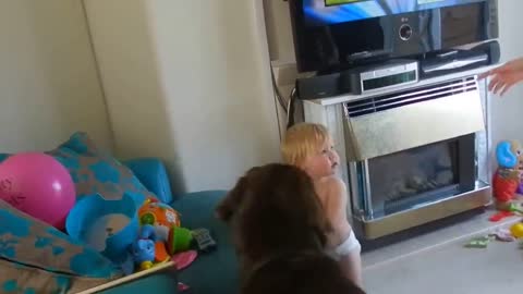 Baby laughing at dog playing with a balloon