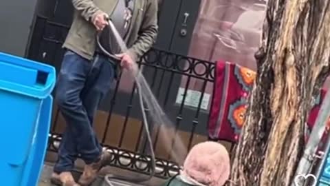 Homeless woman bing sprayed with a hose