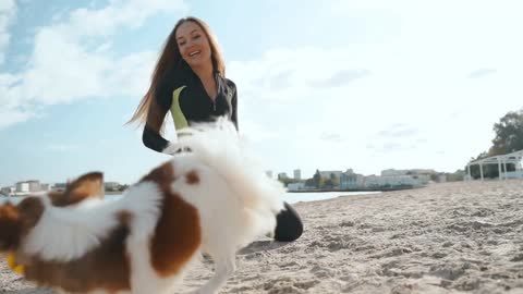 Young adult sportswoman spending day on beach with little dog