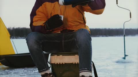 A Man Drinking Coffee While Ice Fishing