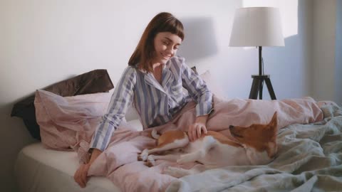 Young cute girl up to the soft morning sunlight in a minimalistic white room and finds her pet dog