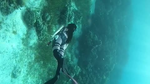 A girl diving under the deep sea with cool outfit