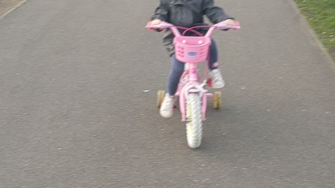 Cute toddler learns to ride her bicycle