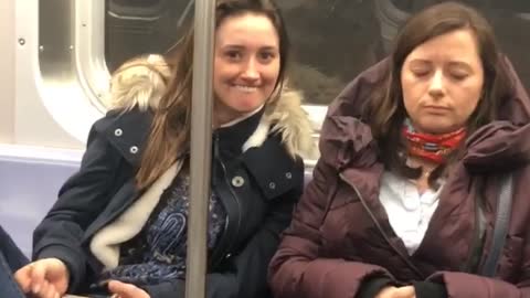 Girl on subway makes silly face at a sleeping woman