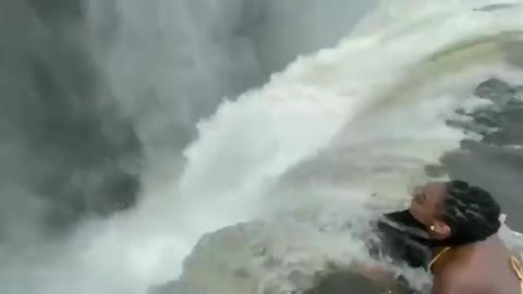 Woman laying down inches before a massive 380 feet drop, devils pool - Victoria falls