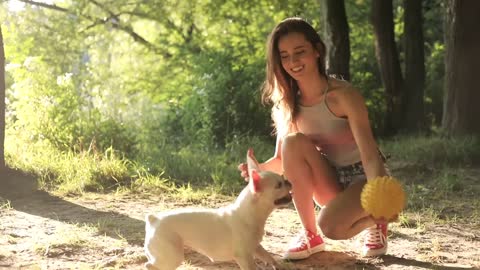 Young Brunette Woman and Handsome Man Resting in the Forest Couple Playing with Pet on the Grass