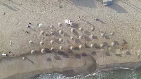 Sunny tourism beach, zoom out aerial shot