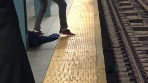 Man with long curly black hair sings on subway platform