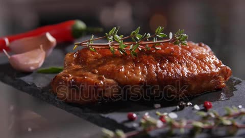 Amazing view of delicious grilled beef with herbs and spices on the stone board. Close-up