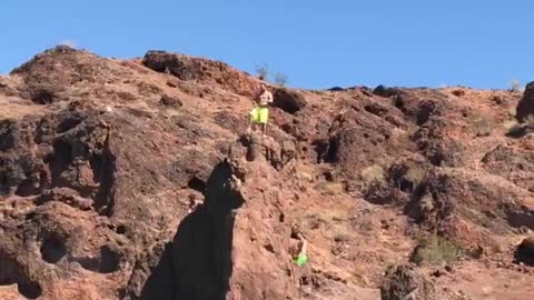 Guy green shorts jumping off cliff into water