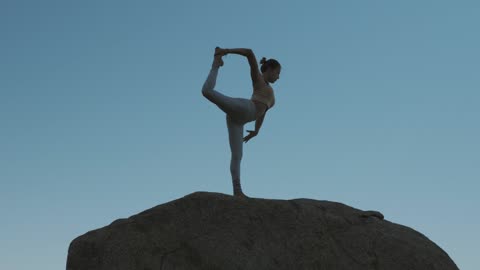 Woman doing yoga on a boulder