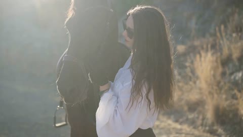 Confident professional equestrian stroking horse face standing in sunrays outdoors