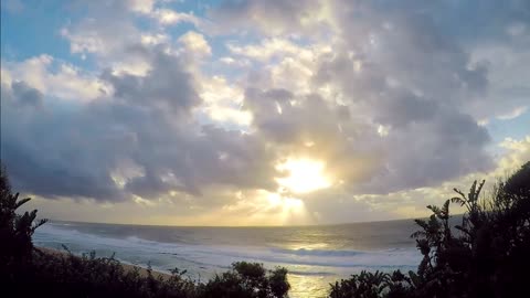 Sun Rising Over The Sea Horizon Before Hiding Over Thick Clouds Formation in Time Lapse Video.