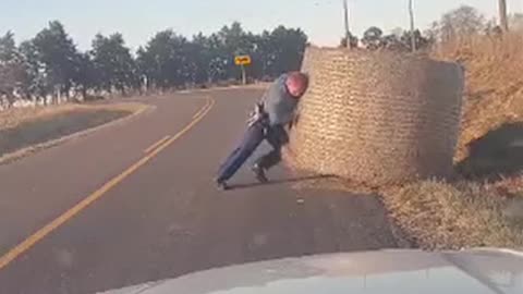 A state trooper got his leg workout in for the day moving this big hay bale out of the road!