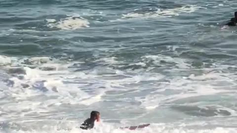 Man in black wet suit with red surf board