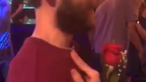 Guy in striped shirt at nightclub buys rose for his friend