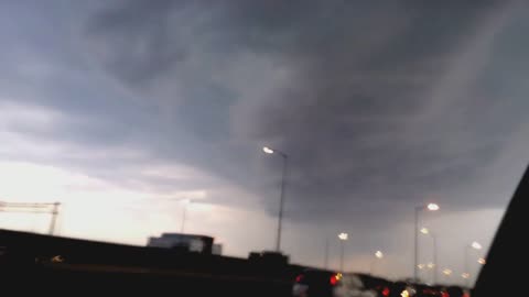 Driving in a big city and seeing a large tornado in the sky